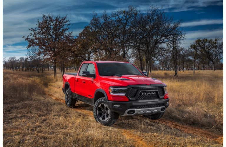 2020 Ram 1500 EcoDiesel Ram Rebel configuration exterior shot with red paint color parked on a dry grass clearing near bare trees