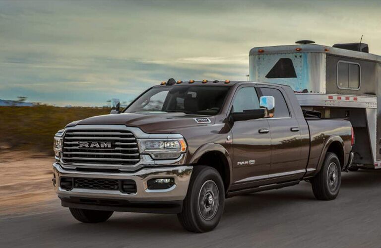 2019 Ram 2500 exterior shot with gray brown paint color towing a trailer through a country highway