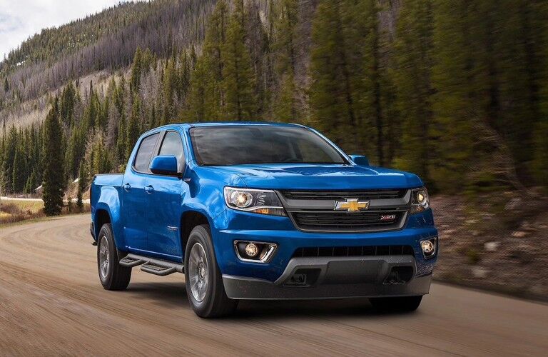 Front passenger angle of a blue 2020 Chevy Colorado driving on a rural road