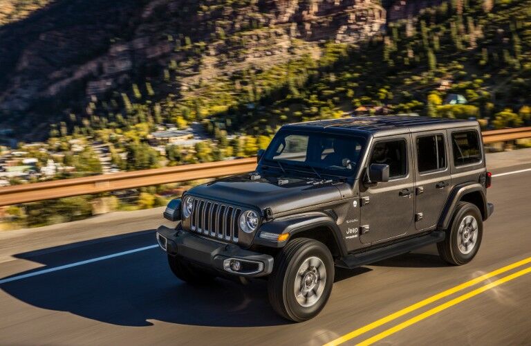 2020 Jeep Wrangler Sahara exterior overhead shot driving on a highway near a mountain range