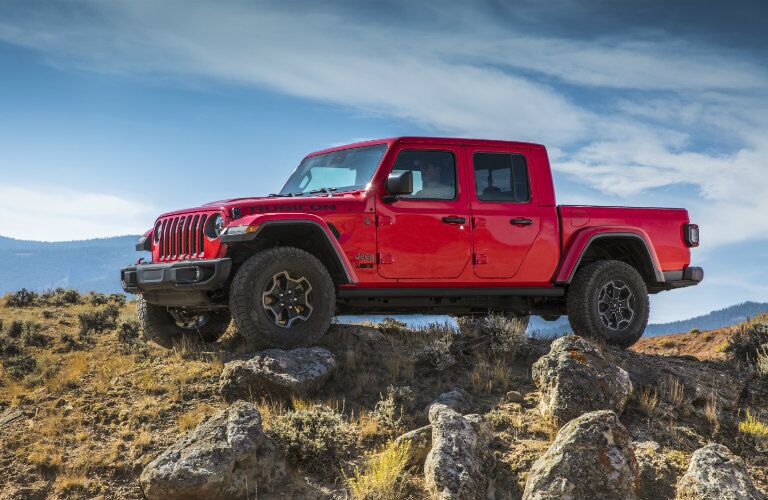 2020 Jeep Gladiator exterior side shot with firecracker red paint color parked on a plain of grass covered in rocks