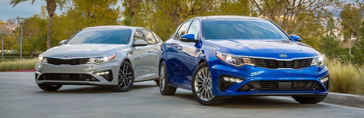 Exterior view of a blue 2019 Kia Optima and a silver 2019 Kia Optima