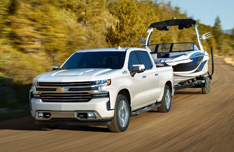 Front driver angle of a white 2020 Chevrolet Silverado 1500 towing a boat