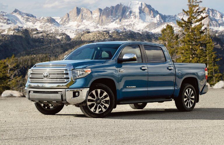 Front driver angle of a blue 2020 Toyota Tundra parked in front of snowy mountains