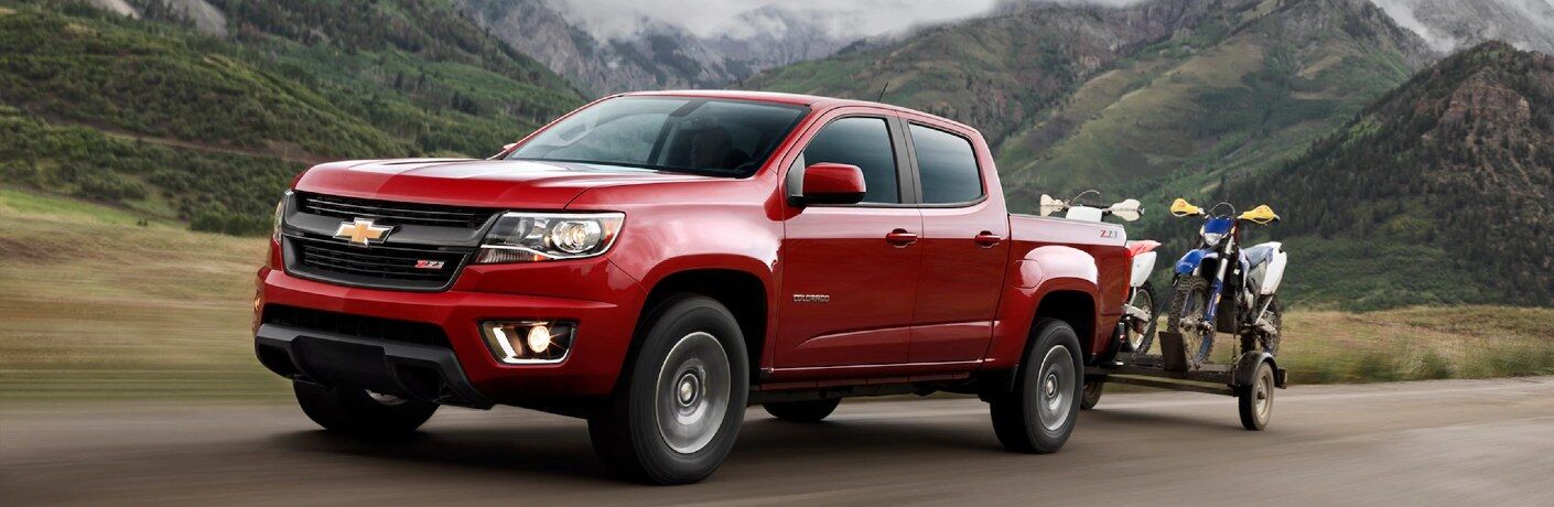 Front driver angle of a red 2020 Chevy Colorado pulling a trailer with dirtbikes