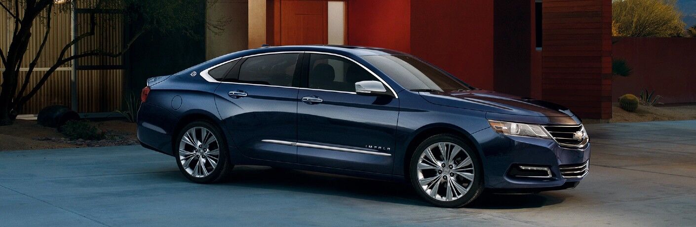 Front passenger angle of a blue 2019 Chevrolet Impala parked by a home