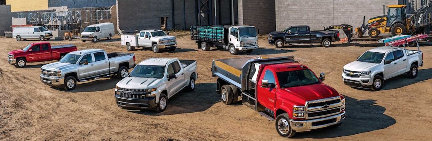 Many Chevrolet commercial vehicles parked at a worksite
