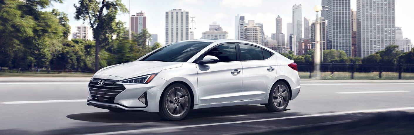 Front driver angle of a white 2020 Hyundai Elantra driving in a city