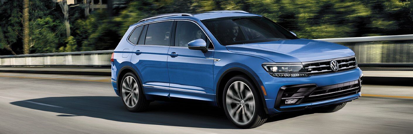 Front passenger angle of a blue 2020 Volkswagen Tiguan driving down a road