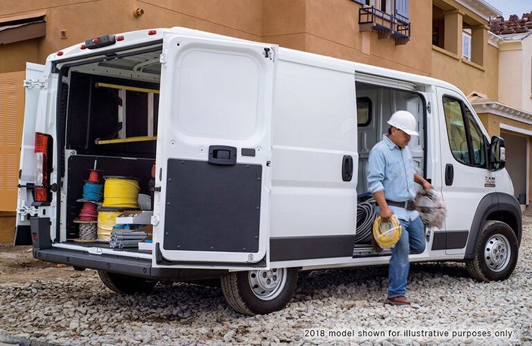 2019 Ram Promaster cargo exterior side shot with white paint color loaded up with equipment as a electrical worker exits