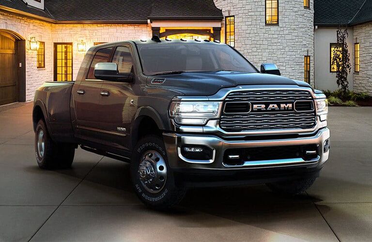 2019 Ram 2500 exterior shot with black gray paint color and headlight on parked on the driveway plaza of a luxury home at night