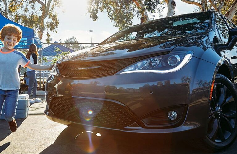 2020 Chrysler Pacifica exterior closeup shot with gray paint color and headlight trim on as a family approaches