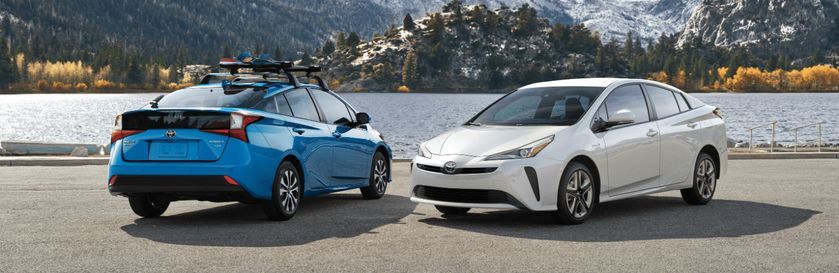 two 2020 Toyota Prius models parked near a lake