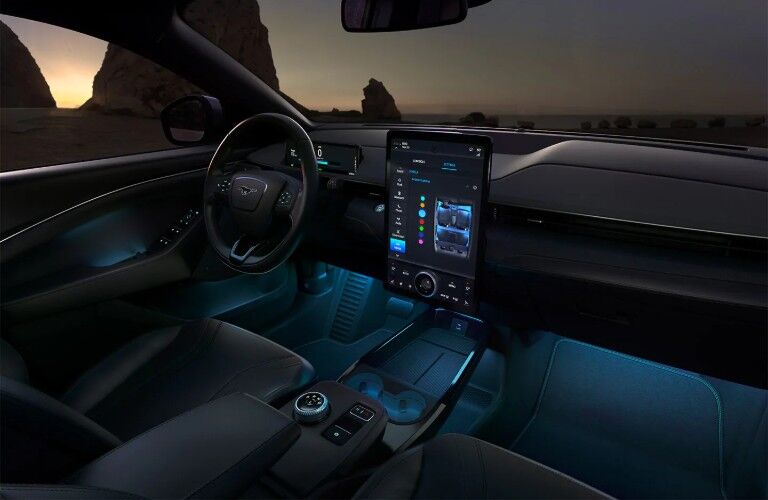 Front interior of the 2021 Ford Mustang Mach-E showing the touchscreen, steering wheel, and ambient lighting