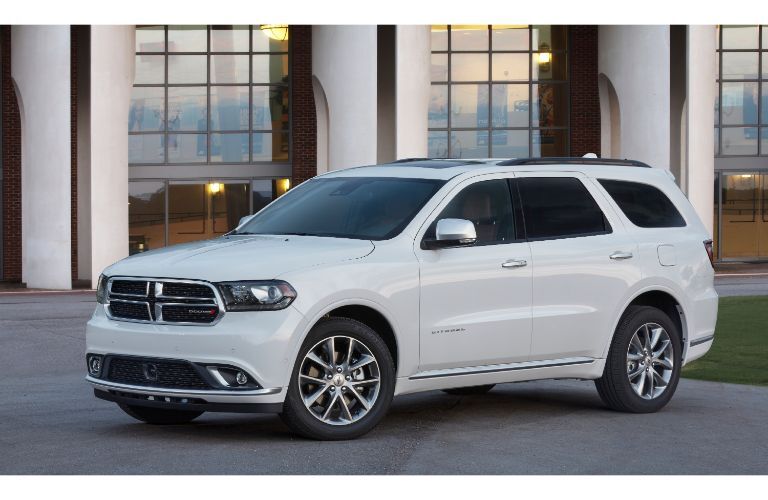 2020 Dodge Durango Citael exterior shot with white paint color and chrome accents parked in front of a building with glass frames and white pillars