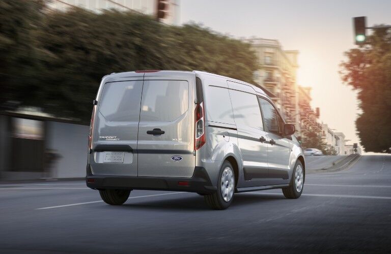 Rear passenger angle of a grey 2020 Ford Transit Connect driving on a city street