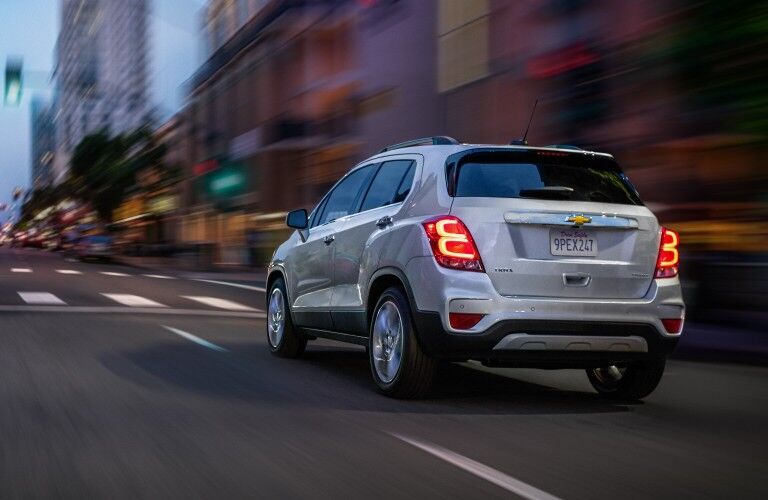 Rear driver angle of a silver 2020 Chevrolet Trax driving down a city street