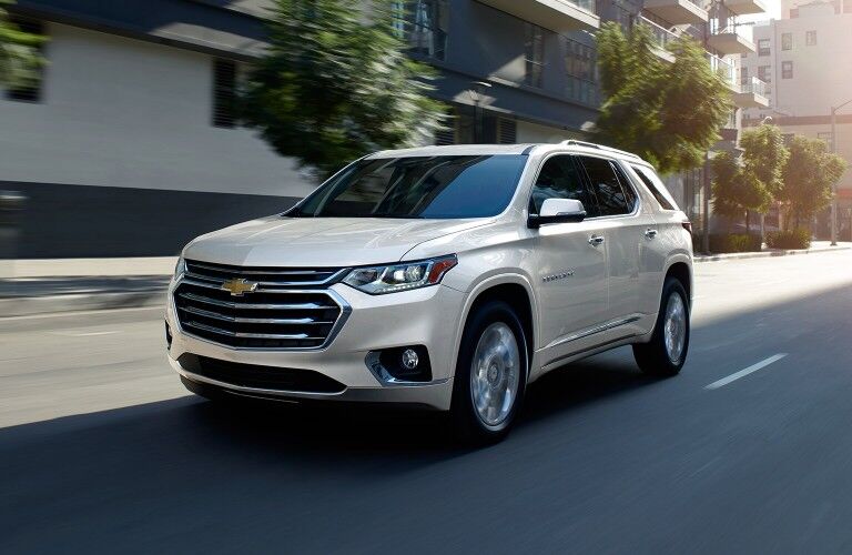 Front driver angle of a white 2020 Chevrolet Traverse driving down a city street