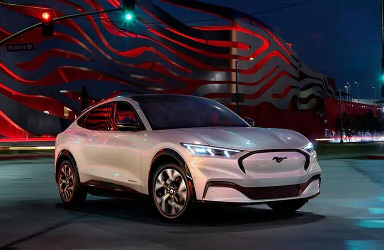 Front passenger angle of a white 2021 Ford Mustang Mach-E parked in a city at night