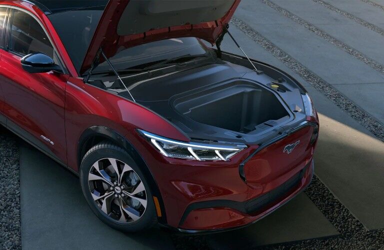 Front passenger angle of a red 2021 Ford Mustang Mach-E with its hood open to show the exterior trunk space