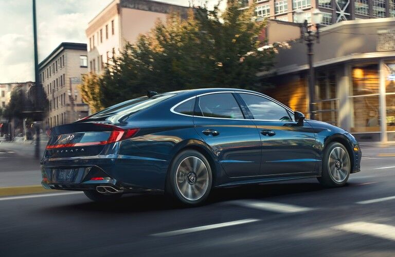 Rear passenger angle of a blue 2020 Hyundai Sonata driving down a road
