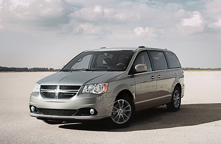 2020 Dodge Grand Caravan exterior front shot with silver gray paint color barked on a barren lot of cracked earth under a cloudy sky